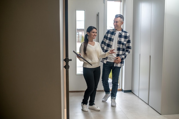 Free photo realtor smiling woman showing cheerful interested middleaged man her new home during day