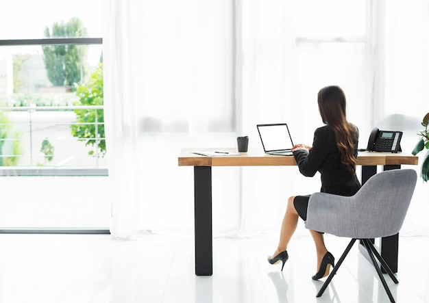 Free Photo rear view of a businesswoman using laptop in the modern office interior