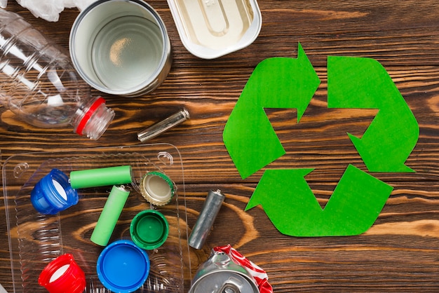 Free photo recycle logo and various recyclable garbage on wooden desk