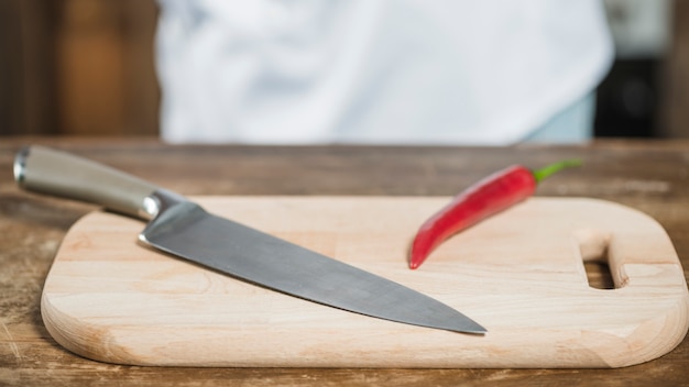 Free photo red spicy chili pepper and sharp knife on chopping board