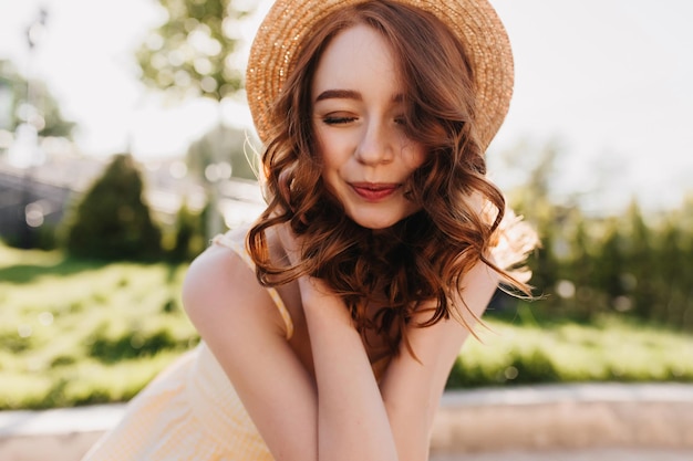 Free Photo relaxed ginger girl smiling with eyes closed outdoor photo of romantic redhaired woman in elegant hair posing on nature background