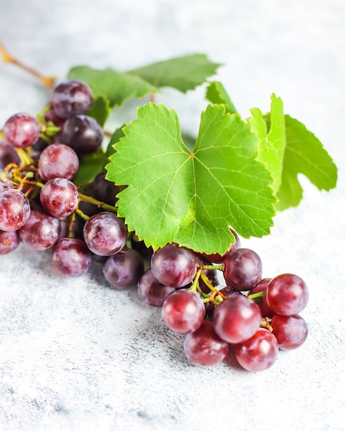 Free photo ripe red grape with leaves on white .