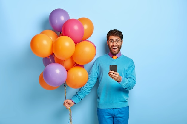 Free photo satisfied guy with balloons posing in blue sweater