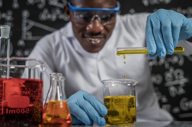 Free photo scientists drop yellow chemicals into the glass at the laboratory