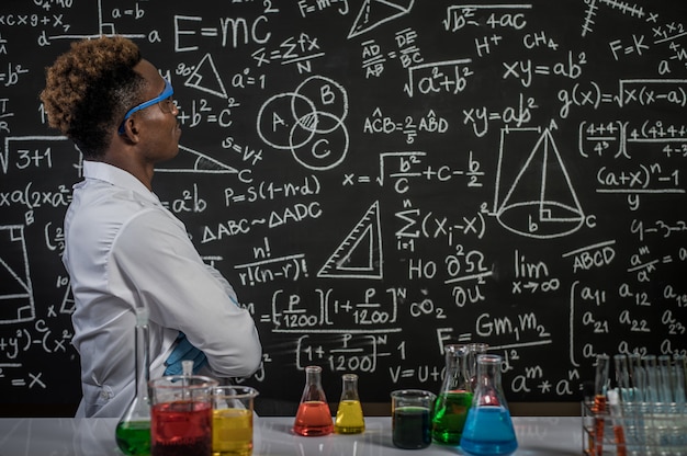 Scientists wear glasses and fold their arms to see the formula in the laboratory