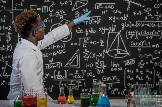 Scientists wear glasses and point to formulas on the blackboard in the laboratory