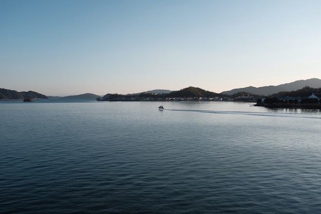 無料Photo 建物に覆われた丘と青い空の下の緑に囲まれた海