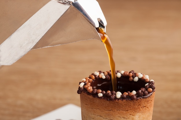 Free photo selective focus shot of coffee pouring in a biscuit cup on a wooden surface