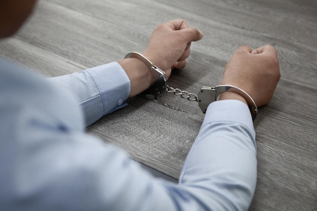 Free Photo selective focus shot of male hands in handcuffs on a wooden table