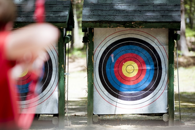 Free photo selective focus shot of a target with a blurred person using bow and arrow