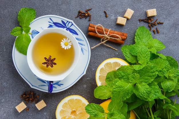 Free photo set of mint leaves, lemon, sugar, dry cinnamon and a cup of chamomile tea