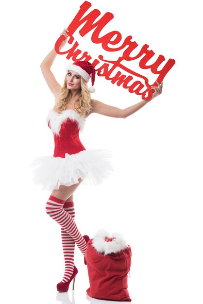 Sexy woman in santa costume posing on white wall