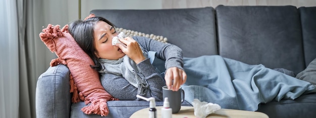 Free Photo sick woman lying on sofa at home catching cold young girl freezing from heating problem in her