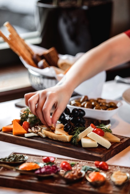 Foto gratuita vista laterale di vari tipi di formaggio con uva matta e miele sul piatto di legno