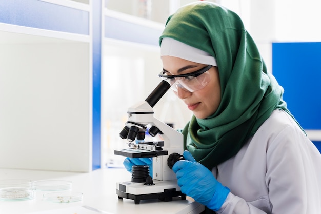 Free Photo side view of female scientist with hijab and microscope