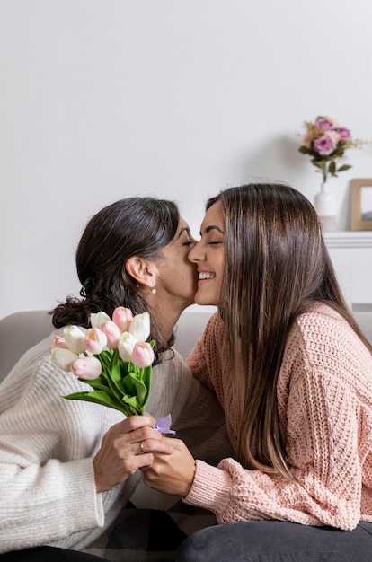 Free photo side view girl offering flowers to mom