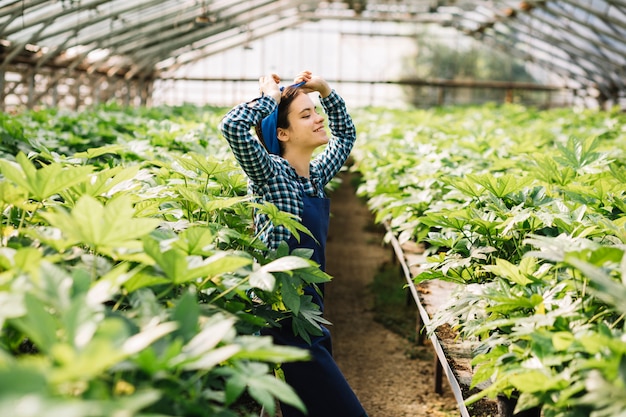 Free photo side view of a happy female gardener standing in greenhouse