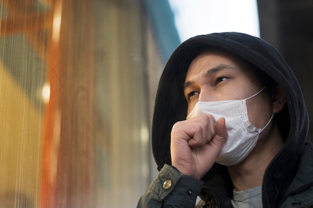 Free photo side view of man coughing while wearing a medical mask