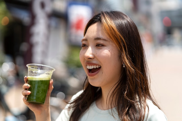 Foto gratuita bevanda della holding della donna di smiley di vista laterale