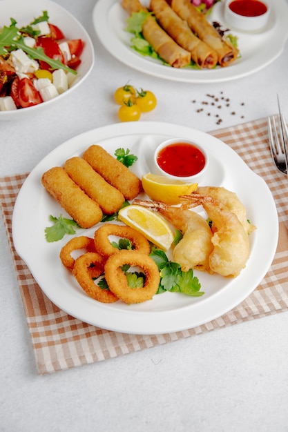 Free photo side view of squid and shrimp tempura and fried cheese sticks on a white plate