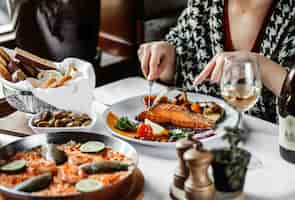 Foto gratuita vista laterale di una donna che mangia salmone al forno con verdure al tavolo th