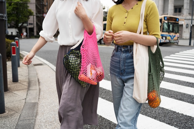 Free photo side view women carrying fabric bags