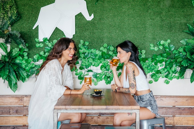 Free photo side view of women drinking beer at table