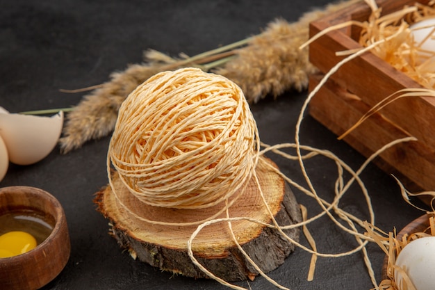 Side view of yellow chaws in a wooden box rope spikes eggs spoons on black background