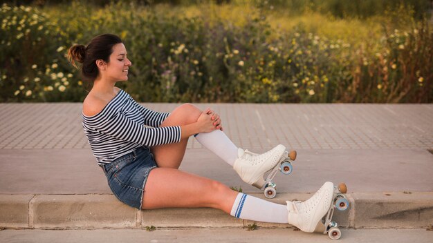 Side view of a young woman wearing roller skate stretching her leg