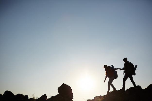 Free Photo silhouette of couple climbing mountains