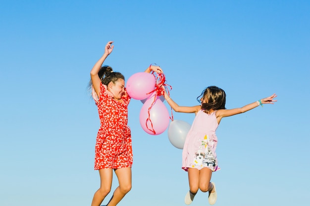 Free photo sisters jumping with balloons