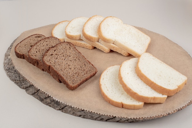 Foto gratuita pane bianco e marrone fresco affettato sul piatto di legno. foto di alta qualità