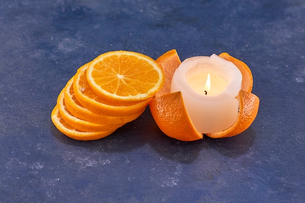 Free photo sliced oranges and melted candle on a gray surface