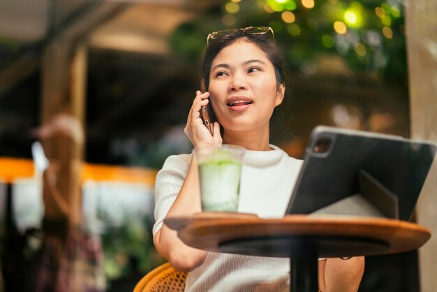 Free photo smart attractive positive asian digital nomad female wearing casual cloth work remote new normal lifestyle hand use tablet tele conference onlive videocall meeting remote at coffeeshop cafe