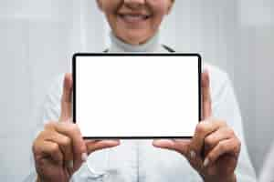 Free photo smiley doctor holding a blank tablet