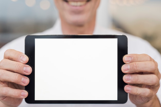 Free photo smiley man holding an empty tablet