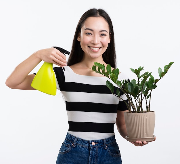Free photo smiley woman spraying flower leaves