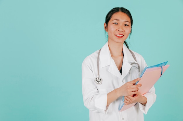 Foto gratuita sorridente medico asiatico con stetoscopio e cartella