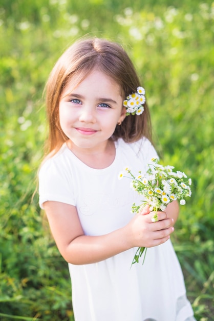 Free photo smiling beautiful girl holding bunch of white flowers