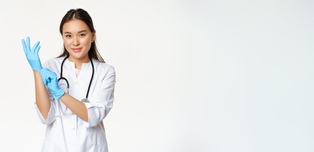 Foto gratuita la dottoressa asiatica sicura e sorridente ha indossato guanti medici che si preparano per l'esame del paziente st