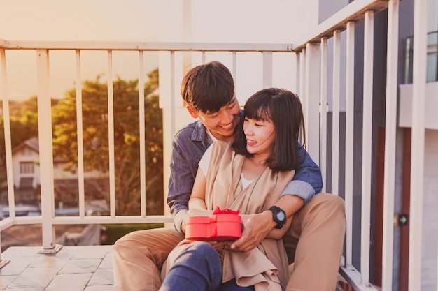 Free Photo smiling couple sitting on the floor with a red gift