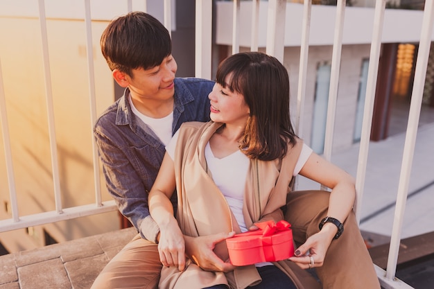 Free Photo smiling couple sitting on the floor with a red gift