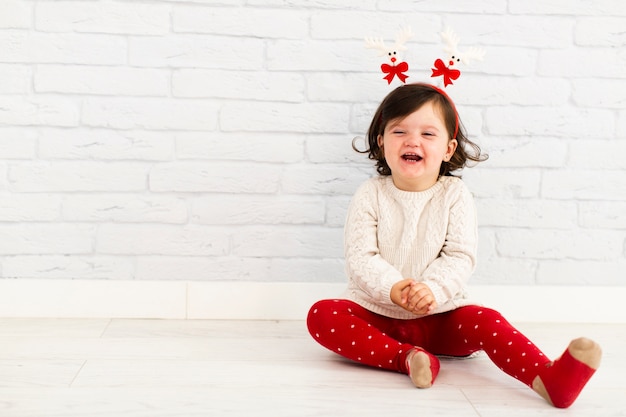 Free photo smiling girl sitting next to white wall