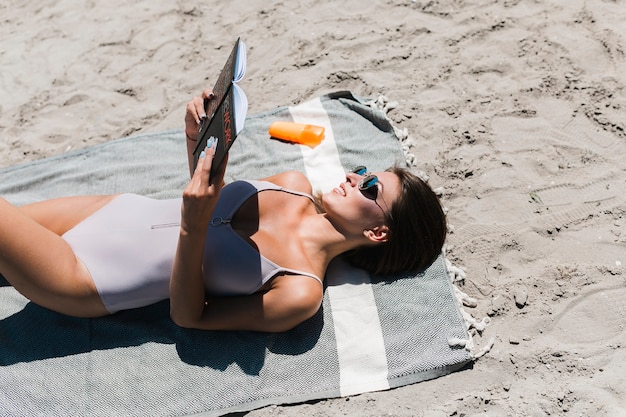 Free Photo smiling woman reading book on beach