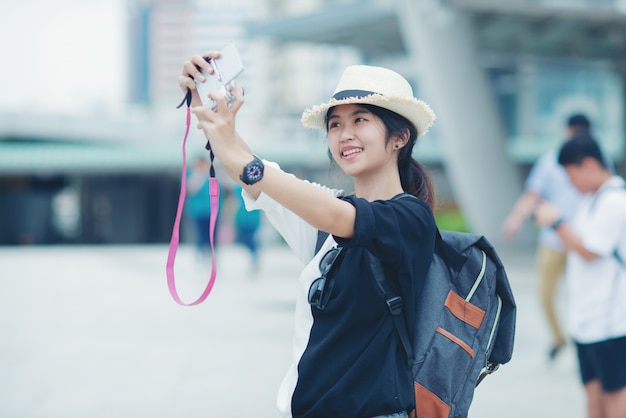 無料Photo 屋外を歩く女性、歩道とバックグラウンドで建物の街の景色を眺めながら若い女性。