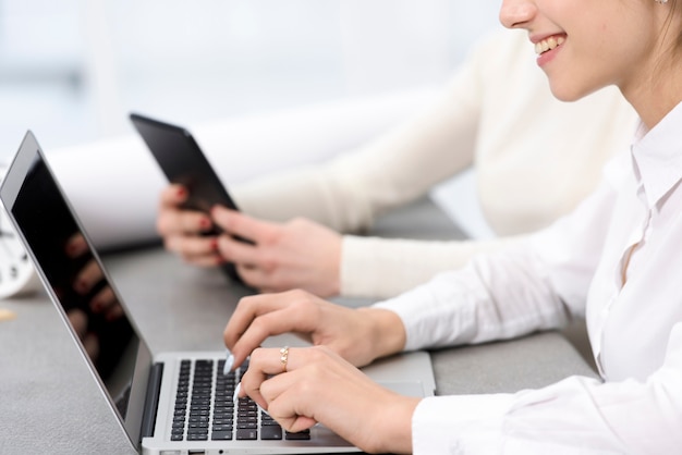 Free photo smiling young businesswoman typing on laptop over the desk