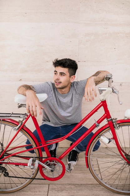 Smiling young teenager sitting at the roadside with bicycle