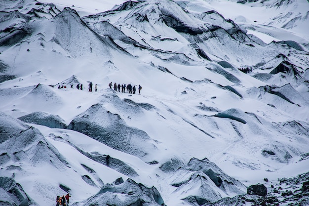 Free photo snowy rugged white mountains with the hiking travelers