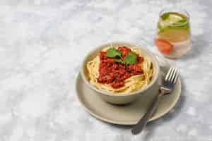 Free photo spaghetti bolognese and lemonade on grey concrete