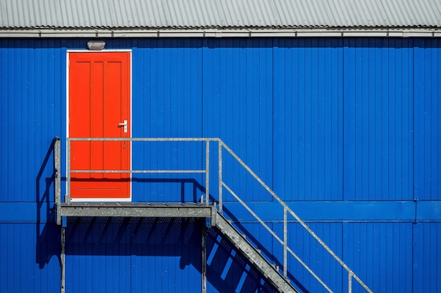 Free photo staircase near the blue wall of a garage leading to the red door